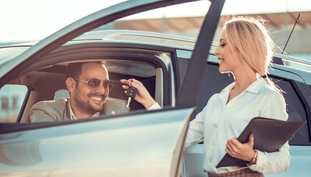 Car dealership.Young man receiving car key from saleswoman.